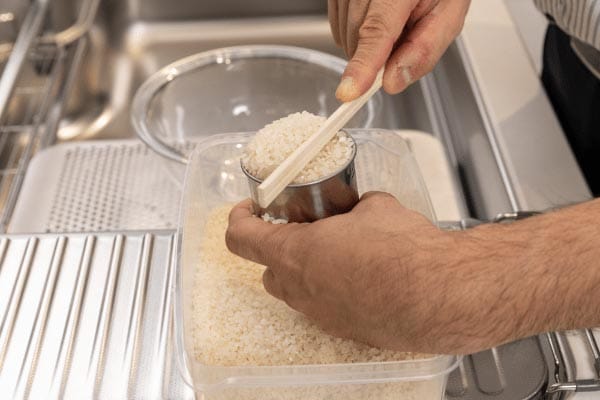 お米を計量カップに山盛りに入れ軽くゆすってカップに詰め込み、すり切りで正しく1合を測る。