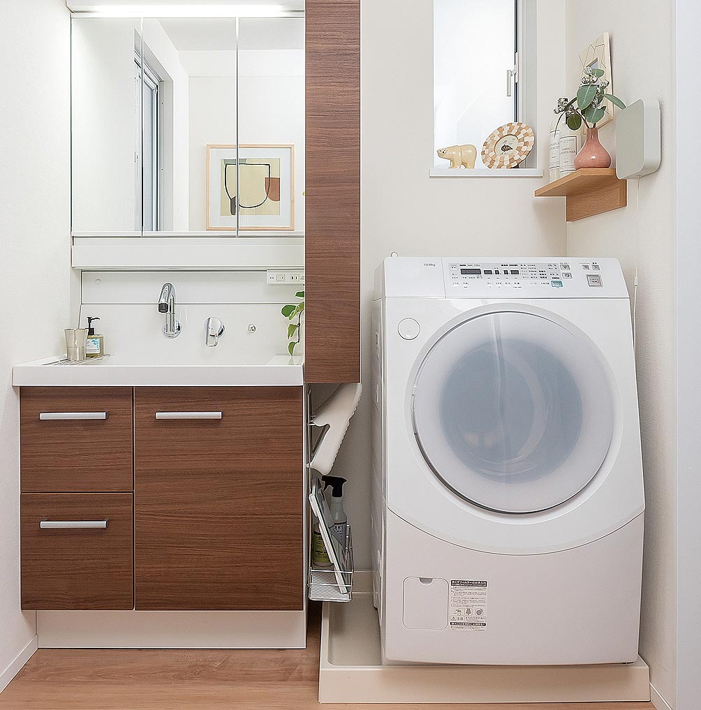 写真：洗面化粧台と洗濯機の間に収納がある洗面室