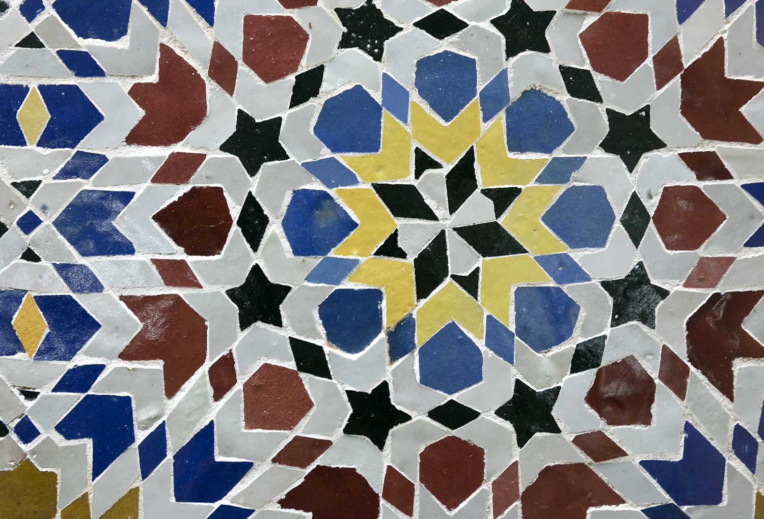 14世紀以降、モロッコからイベリア半島を通じてスペインへと、様々な色を用いたカットワークモザイクの手法が伝わった（画像は20世紀にモロッコで作られたタイル）
