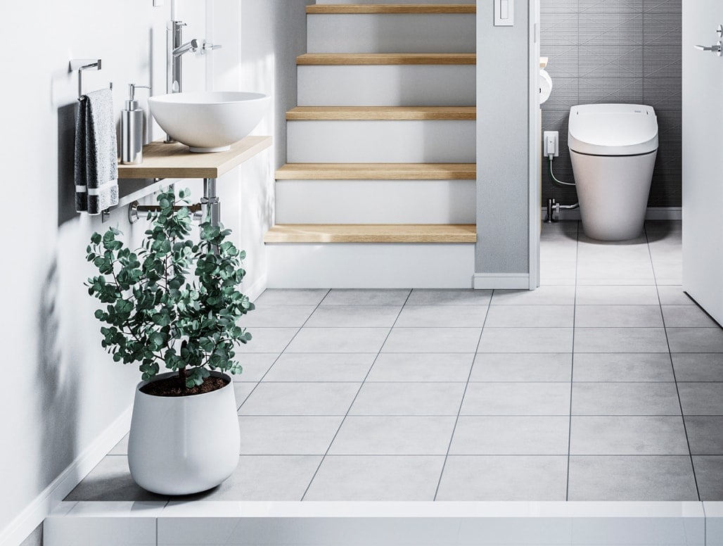 ミニマムなグレーの空間に清潔感あるホワイトのトイレと手洗器、白木と植栽のグリーンが程よい温もりを演出。