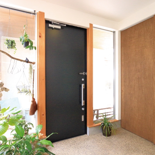 木を使ったナチュラルな玄関空間に、あえて異素材の黒い鋼板製のドアをコーディネート